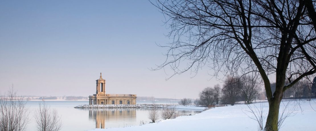 A building on the edge of a snowy waterfront in winter sunlight