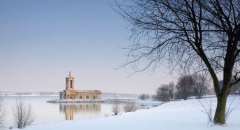 A building on the edge of a snowy waterfront in winter sunlight