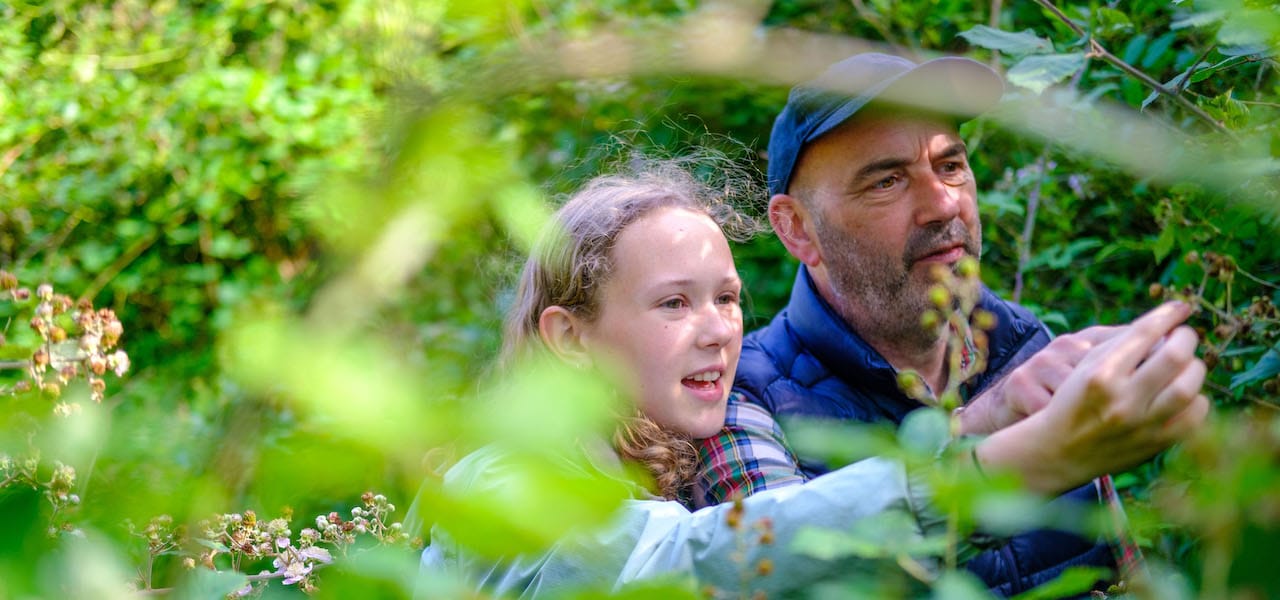 Father and daughter looking at hedgerow plants
